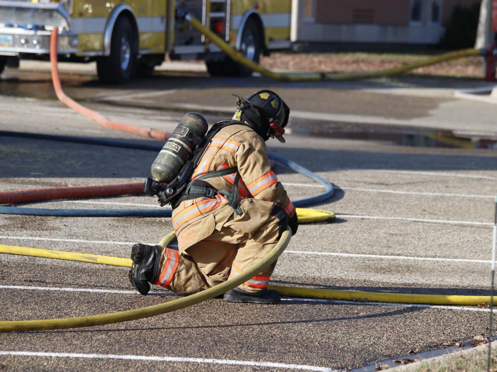 Firefighter crouching down, holding hose