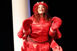 student dressed as a crab, on stage singing during a play performance