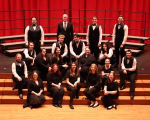 students sitting on stage wearing formal concert attire of black suits and/or black dresses