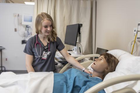 Nursing standing to talk to patient in SIM lab