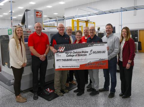 Group of people holding a giant donation check from Gene Haas Foundation. 