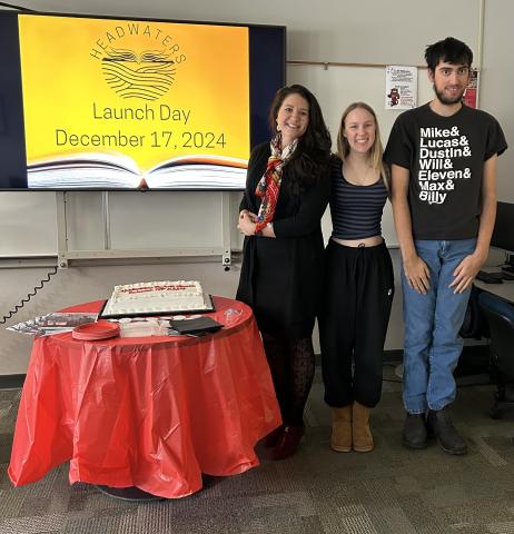 A teacher and 2 students are standing side by side near a screen showing the December 17th launch of the Headwater publication.