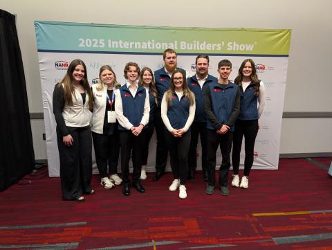 Group of college students standing in front of a sign designating an event called 2025 International Builders' Show