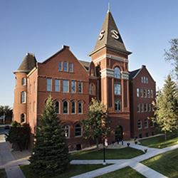 Old Main building at NDSCS surrounded by clear blue skies and green grass and trees